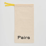 A beige canvas drawstring pouch with a bright yellow tie and the word 'Pairs' printed in black at the bottom, shown on a light gray background.