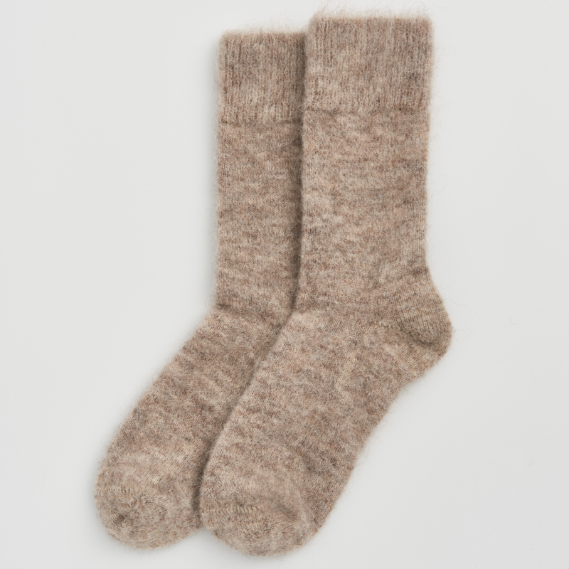 A pair of fuzzy, heathered knit socks in a warm taupe-beige color, displayed flat against a clean, light gray background.