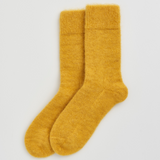 A pair of fuzzy, mohair-style mustard yellow socks shown flat against a light gray background.