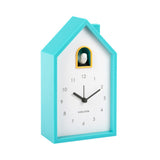 Turquoise clock shaped like a house with a white face on a white background