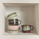 Set of ceramic mugs with different designs on a white shelf.
