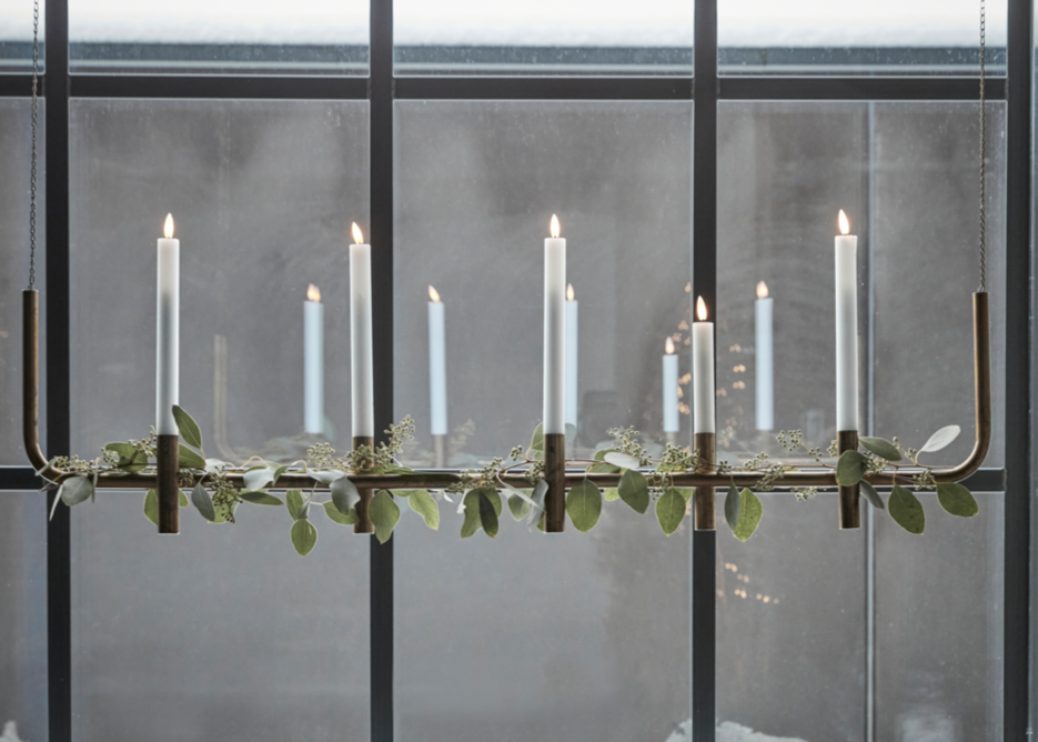 Decorative candle holder with candles in front of a large window