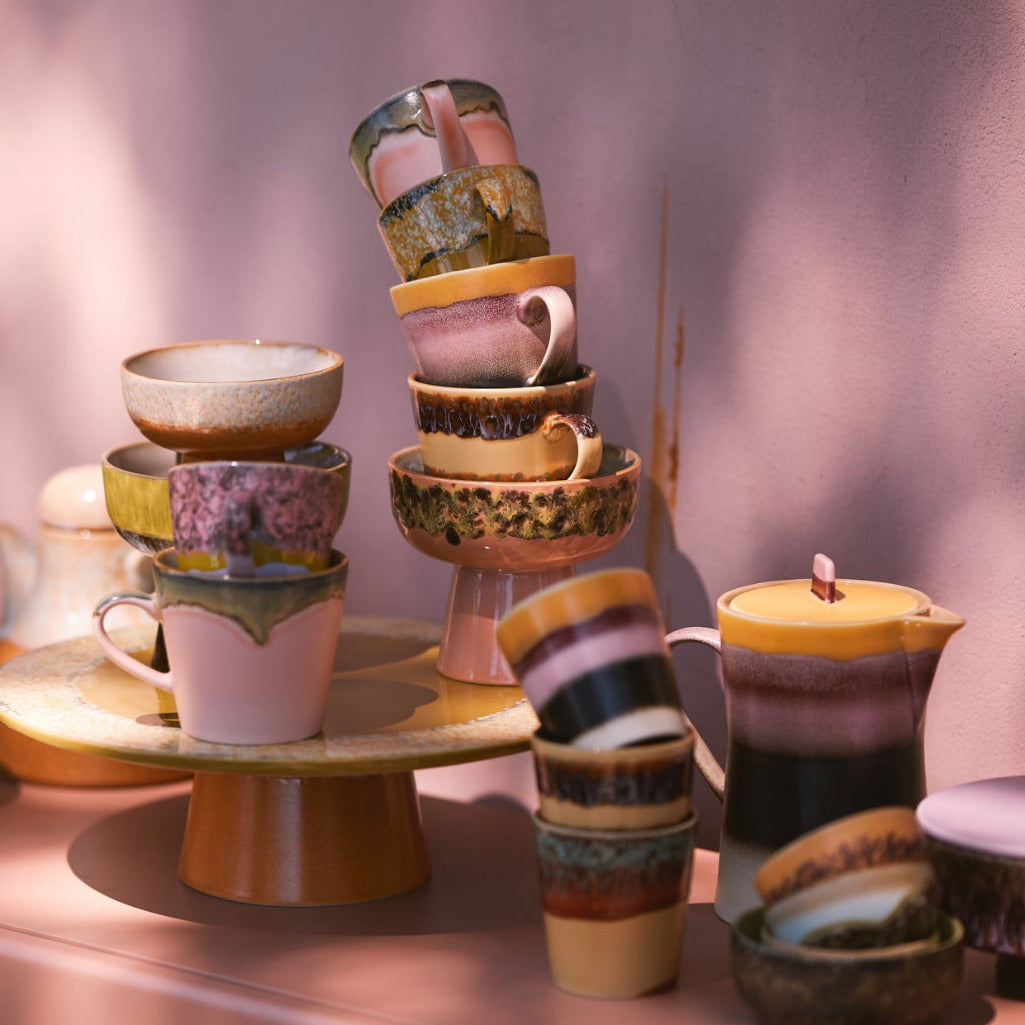 Collection of colorful ceramic items on a pink surface with a soft pink background