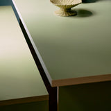 Light green table with decorative items including a vase with yellow flowers, a green candle holder, and a beige bowl.