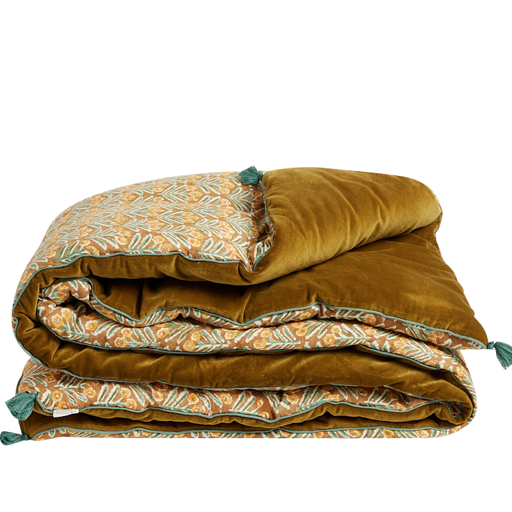 A folded quilted comforter with a rich mustard-gold velvet side and a patterned side featuring teal and orange botanical motifs, set against a plain white background.