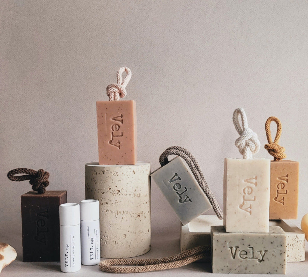 Collection of Vely products including soap bars and containers on a neutral background