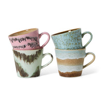 Set of four ceramic mugs with textured, multicolored designs on a white background
