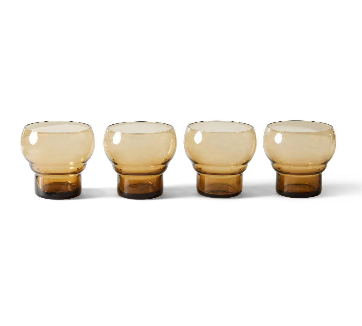 Four amber glass tumblers on a white background