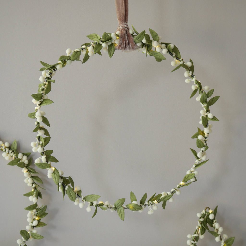 Circular mistletoe green leaf and white berry garland on a plain background
