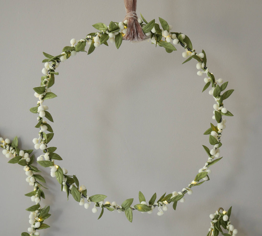 Circular mistletoe green leaf and white berry garland on a plain background