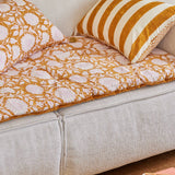 White sofa with orange and white patterned cushions in a living room setting.