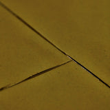 Close-up of a textured surface in warm olive-gold tones with thin dark grout or seam lines crossing diagonally.