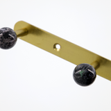 brass hook with black spherical ends on a white background