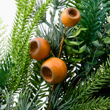 Artificial green foliage with three orange-brown hollow coelacanth-like fruit ornaments attached to stems, photographed against a plain white background.