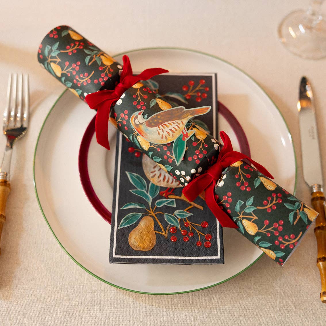 Decorative Christmas cracker with a card on a plate with cutlery