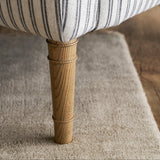 Close-up of a chair leg with striped fabric on a carpeted floor