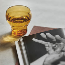 Amber glass on a book with a black and white photograph of hands
