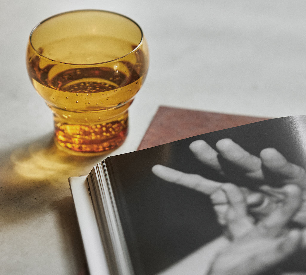 Amber glass on a book with a black and white photograph of hands