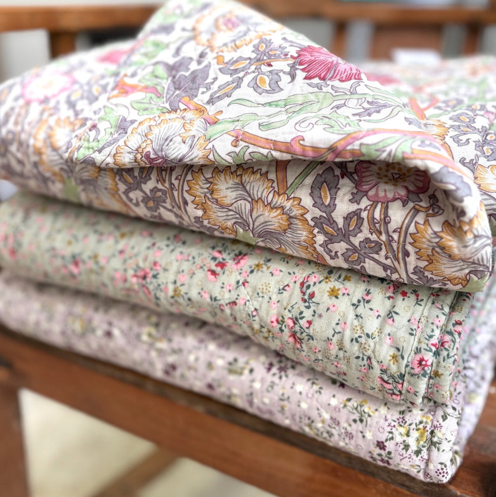 Stack of floral-patterned quilts on a wooden surface