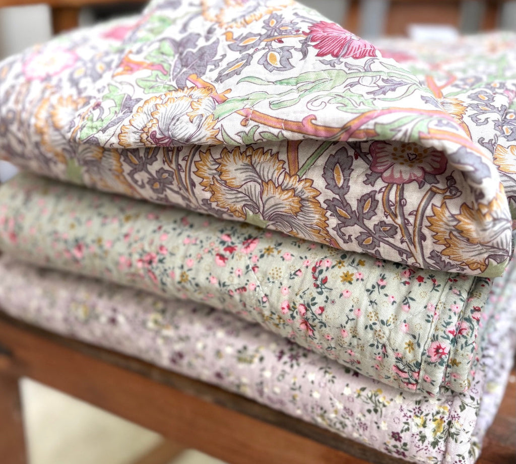 Stack of floral-patterned quilts on a wooden surface