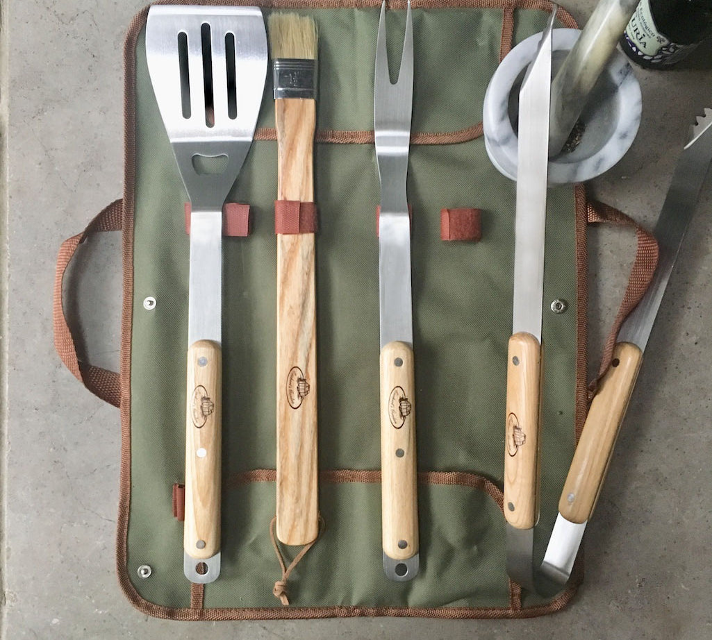 Set of barbecue tools with wooden handles on a green carrying case.