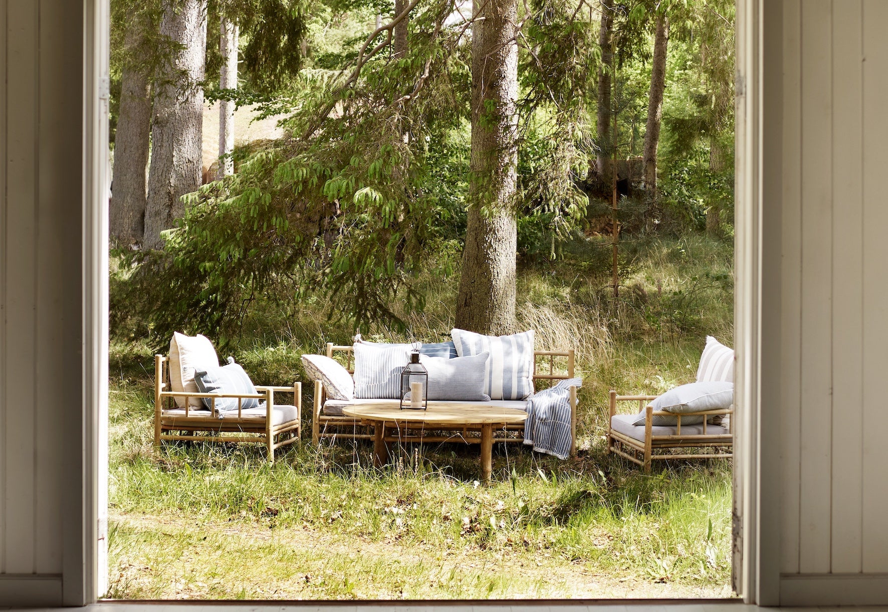 Outdoor bamboo sofa and chairs wooden furniture and cushions in a forest setting.