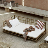 bamboo outdoor sofa with white cushions and a blanket.