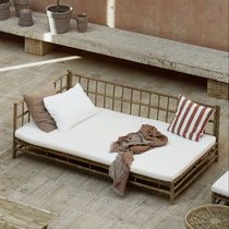 bamboo outdoor sofa with white cushions and a blanket.