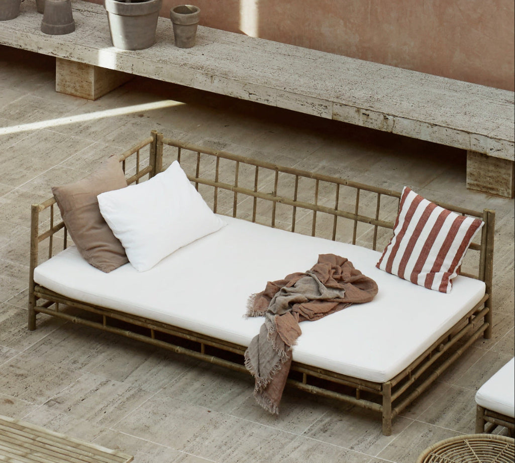 bamboo outdoor sofa with white cushions and a blanket.