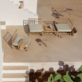 Outdoor seating area with bamboo benches and cushions on a beige patio.