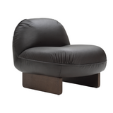 A modern low-profile accent chair with a rounded, bubble-like backrest and seat upholstered in dark charcoal gray leather, supported by a low rectangular dark brown wooden base, shown against a plain white background.