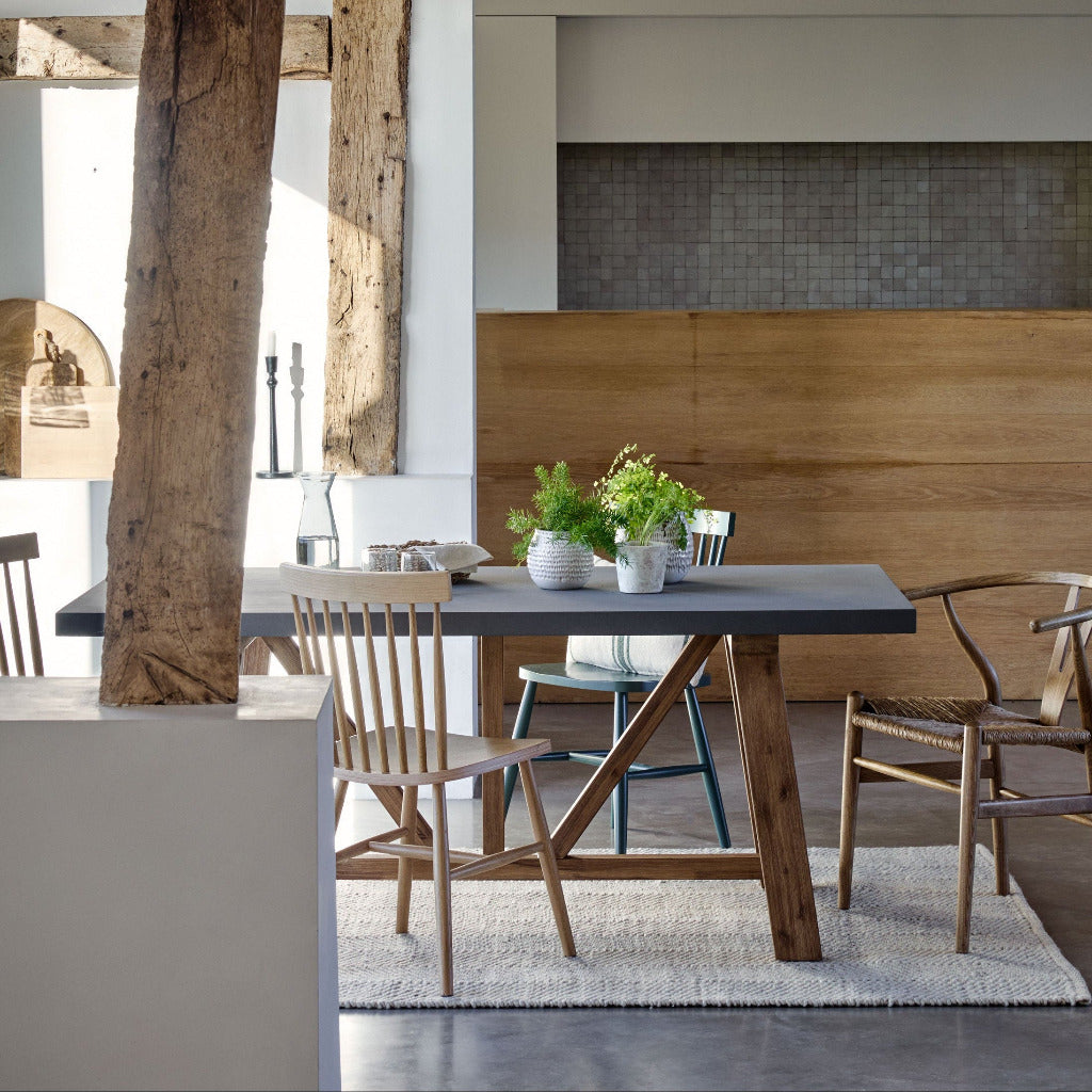 Modern dining area with wooden table and chairs, exposed beams, and a neutral color palette.