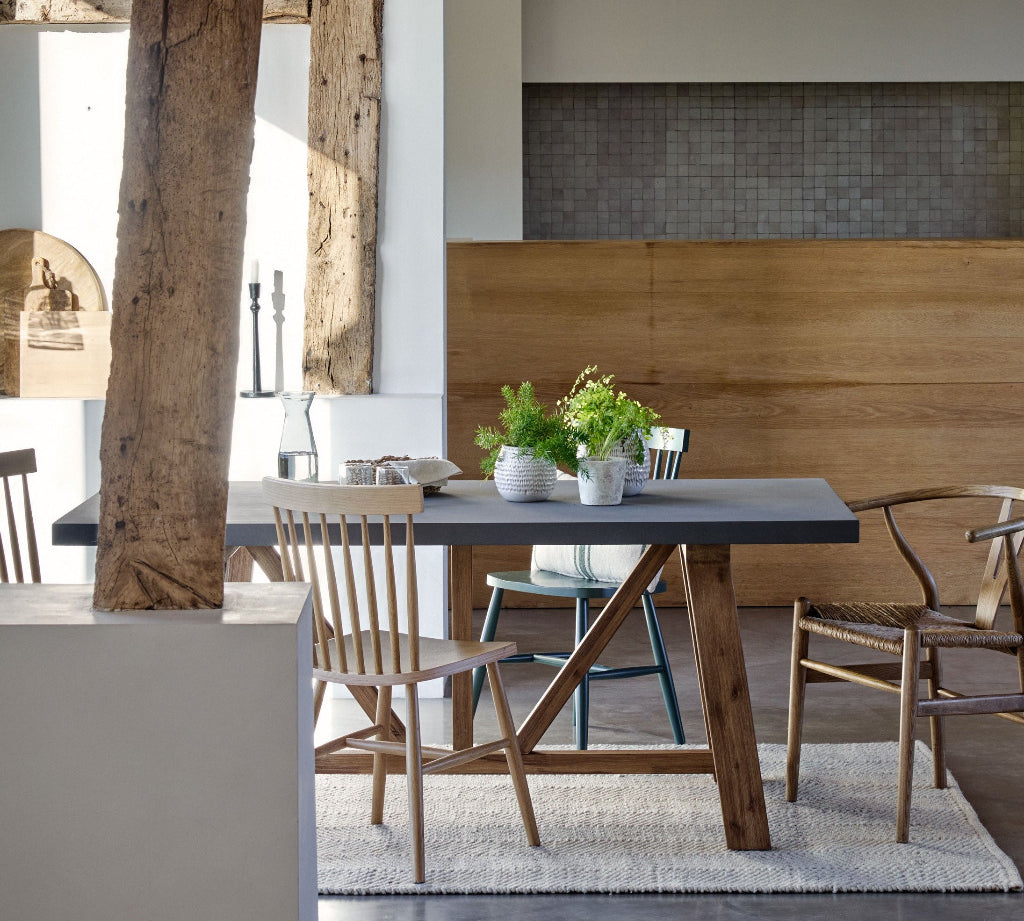 Modern dining area with wooden table and chairs, exposed beams, and a neutral color palette.