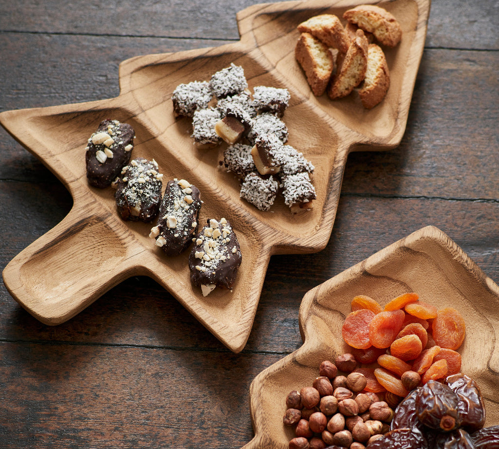Wooden Christmas Tree shaped platters with dried fruits and nuts on a wooden surface