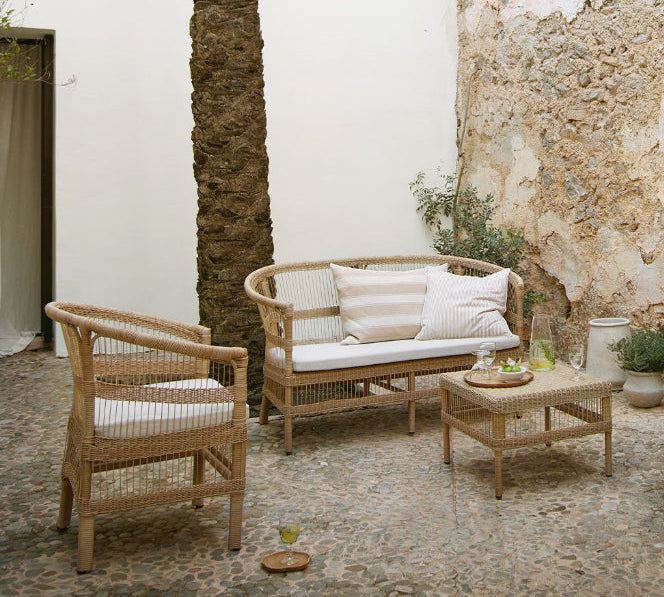 Outdoor patio with rattan furniture and stone walls