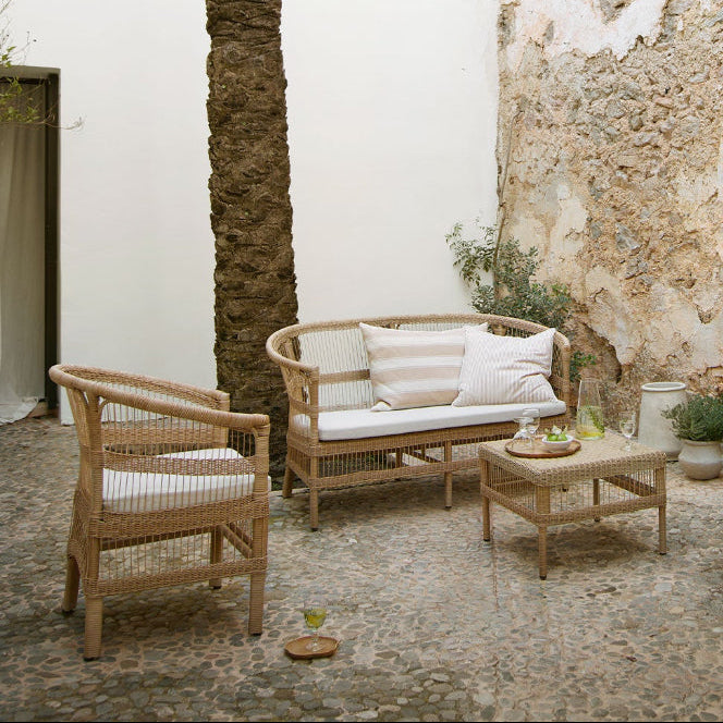 Outdoor patio with rattan furniture and stone walls
