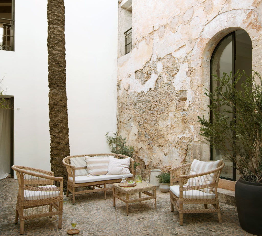 Outdoor patio with rattan furniture and stone walls