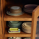 Wooden cabinet with stacked ceramic plates and utensils inside