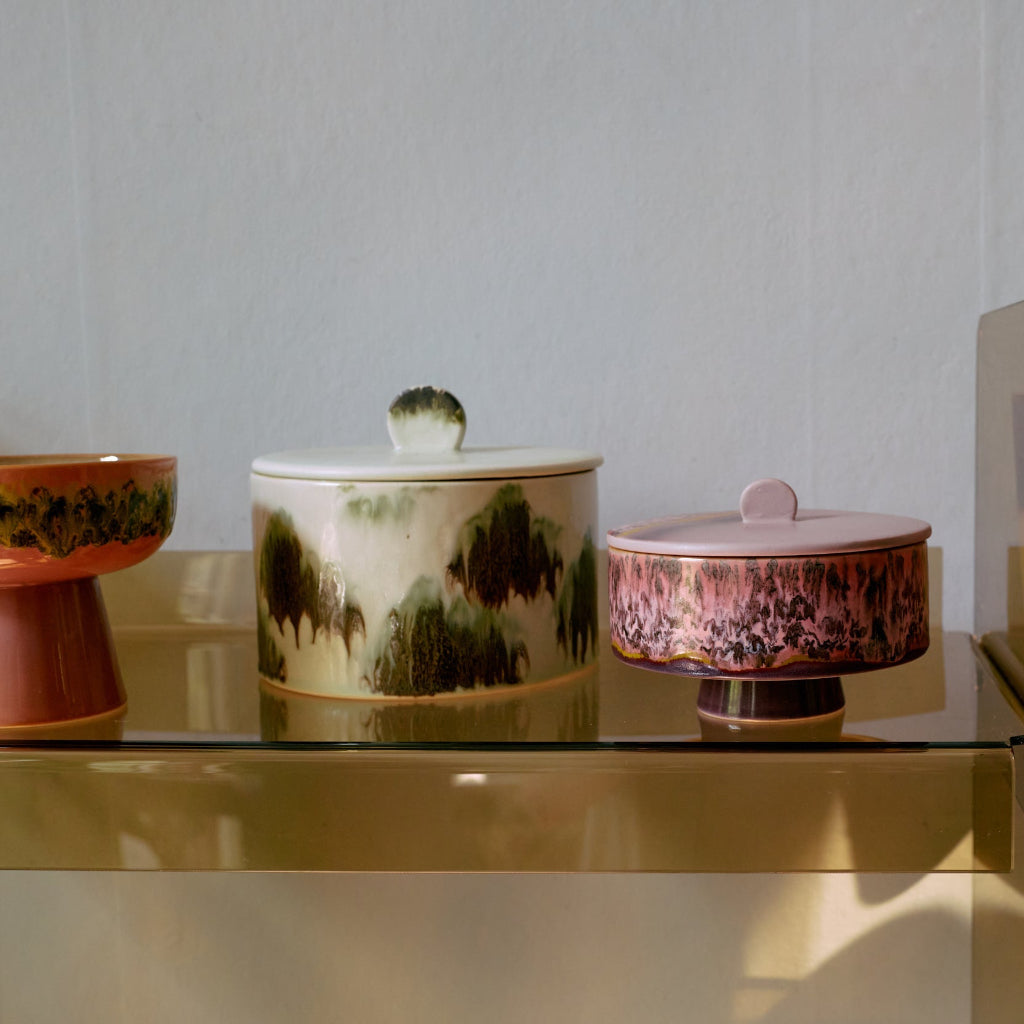 Three ceramic containers with lids on a reflective surface