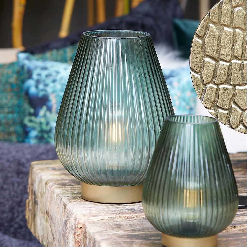 Two ribbed glass vases on a wooden surface with a blurred background