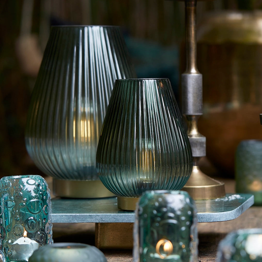 Decorative candles and glass lamps on a wooden surface with a blurred background
