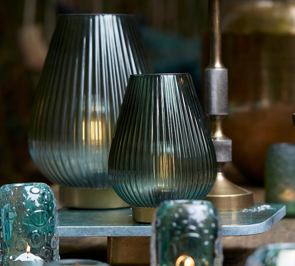 Decorative candles and glass lamps on a wooden surface with a blurred background