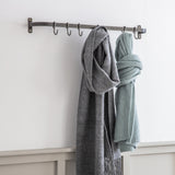 Two scarves hanging on a metal rack against a white wall.