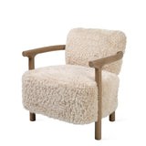A modern accent chair featuring a thick, shaggy cream-colored sheepskin or faux fur upholstery with a natural light brown wooden frame and curved armrests, shown against a solid white background.