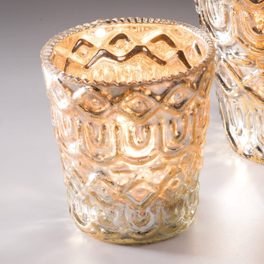 Decorative silver glass candle holder with intricate patterns on a light background