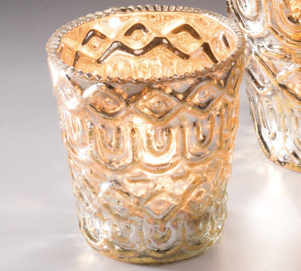 Decorative silver glass candle holder with intricate patterns on a light background