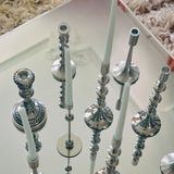 Silver candle holders with white candles on a reflective surface