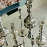 Silver candlestick holders on a reflective surface