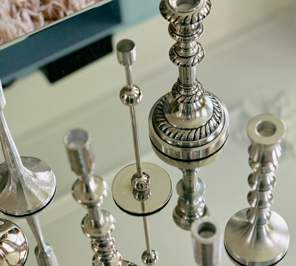 Silver candlestick holders on a reflective surface