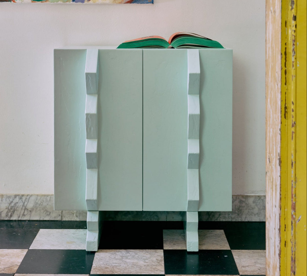 Modern blue cabinet against a white wall with a colorful painting of four people above it.